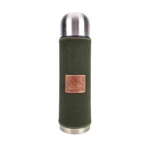 Op de afbeelding: Een roestvrijstalen thermoskan met een groene canvas hoes en een bruine leren patch. De leren patch heeft de tekst "TREK NATURE". De thermoskan heeft een zilveren deksel en bodem.