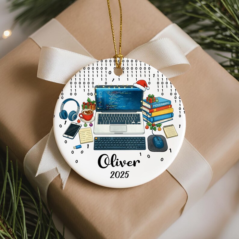 Pu&ograve; includere: Ornamento natalizio rotondo in ceramica bianca con cordino dorato. Raffigura un laptop, una tastiera e un mouse, con un cappello di Babbo Natale sullo schermo. L'ornamento include il nome "Oliver" e l'anno "2025". Numeri binari circondano il design.