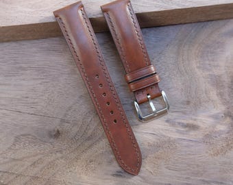 May include: Two brown leather watch straps with decorative stitching. One strap has a silver buckle and a series of holes for adjustment. The straps are made of a smooth, rich brown leather and are designed to attach to a watch face.