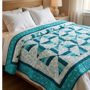 May include: A teal and white quilt with a geometric pattern is displayed on a bed. The quilt features a repeating design of triangles and circles, with a teal border. The bed has white pillows and sheets.