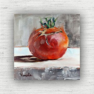 May include: A square oil painting of a ripe red tomato with green stems. The tomato sits on a white surface against a gray and white background. The artist's signature, "Vamola", is in the lower left corner.