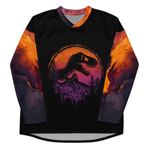 May include: Black long-sleeved jersey featuring a dinosaur graphic within a circular design. The design includes a T-Rex silhouette, mountains, and trees, set against an orange and purple sunset gradient. The sleeves have an orange and purple watercolour design.