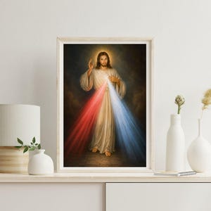 K&ouml;nnte beinhalten: Gerahmtes religi&ouml;ses Kunstwerk, das eine Figur in wei&szlig;en Gew&auml;ndern mit Heiligenschein zeigt. Rote und blaue Lichtstrahlen gehen von der Brust der Figur aus. Das Kunstwerk wird auf einem wei&szlig;en Regal mit einer Lampe und Vasen ausgestellt.