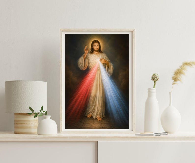K&ouml;nnte beinhalten: Gerahmtes religi&ouml;ses Kunstwerk, das eine Figur in wei&szlig;en Gew&auml;ndern mit Heiligenschein zeigt. Rote und blaue Lichtstrahlen gehen von der Brust der Figur aus. Das Kunstwerk wird auf einem wei&szlig;en Regal mit einer Lampe und Vasen ausgestellt.