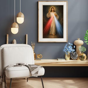 K&ouml;nnte beinhalten: Ein gerahmter religi&ouml;ser Druck zeigt eine Figur in wei&szlig;en Gew&auml;ndern mit Heiligenschein, die eine Hand ausstreckt. Rotes und blaues Licht geht von der Figur aus. Der Druck h&auml;ngt &uuml;ber einem Holzregal mit Dekoration, einem wei&szlig;en Stuhl und H&auml;ngelampen.