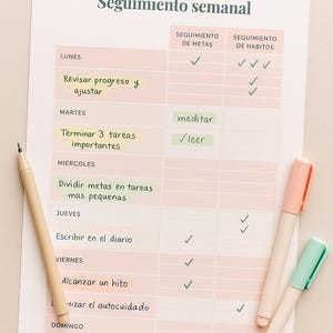 May include: A weekly planner titled "Seguimiento semanal" with a light pink and white color scheme. The planner includes sections for tracking goals and habits, with checkmarks indicating completed tasks. Two pastel-colored pens and a pencil are on the side.