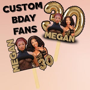 以下が含まれることがあります： 2 人の女性の画像、テキスト「CUSTOM BDAY FANS」、名前「MEGAN」を特徴とするカスタム誕生日ケーキトッパー。 1 つのトッパーには、金色の風船の数字 30 があります。 トッパーは木製の棒の上にあり、ピンク色の背景に設定されています。