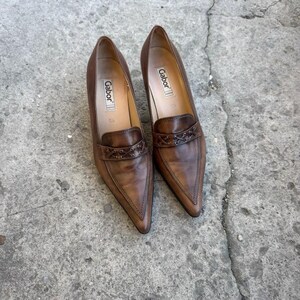 May include: A pair of brown leather Gabor court shoes with pointed toes. The shoes have a low heel and a decorative strap. The Gabor logo is visible inside the shoe.