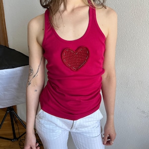May include: A pink tank top with a red crocheted heart on the front.