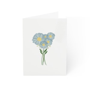 May include: A greeting card with a bouquet of light blue flowers with yellow centers. The flowers are arranged in a cluster with green stems.