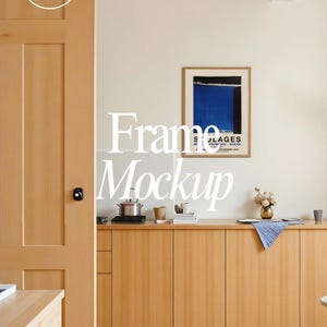 Puede incluir: Escena interior con un mueble y una puerta de madera clara, con una obra de arte enmarcada en la pared. Una olla de acero inoxidable, tazas y libros están sobre el mueble. Las palabras "Frame Mockup" están superpuestas a la imagen, junto con "PSD File" en un círculo.