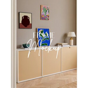 May include: A room interior featuring framed artwork, a lamp, and a cabinet. The artwork includes a vase, floral, and abstract designs. The cabinet has tan doors and a white top. The text "FRAME Mockup" is overlaid on the image.