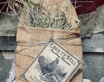 May include: A burlap sack filled with hay, tied with twine, and decorated with a vintage-style label that reads "Liberty Hill Poultry Farms" and "Specializing in Barred Plymouth Rocks Since 1875".