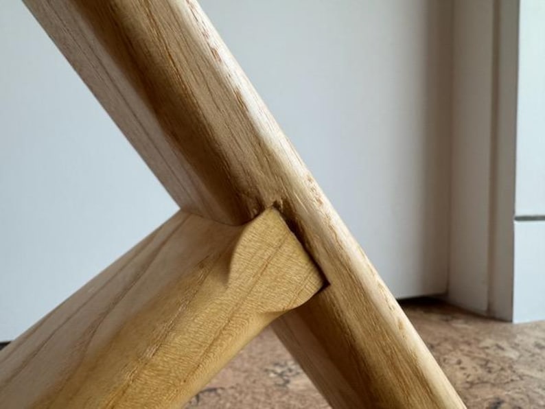 Op de afbeelding: Close-up van een houten meubelverbinding. De lichtbruine houtnerf is zichtbaar. De verbinding is een pen-en-gatverbinding, met een wigvormige pen die in de uitsparing is geplaatst.