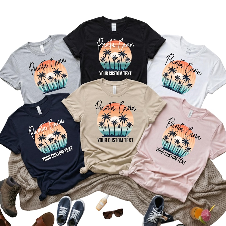 May include: A collection of t-shirts in various colors, including gray, black, white, navy, tan, and pink. Each shirt features a sunset design with palm trees and the words "Punta Cana" and "YOUR CUSTOM TEXT".