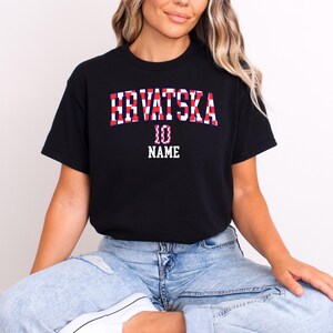 May include: A black short-sleeved t-shirt featuring the text HRVATSKA in a red and white checkered pattern, with the number 10 and the word NAME printed in white block lettering below the main text on the front of the garment.