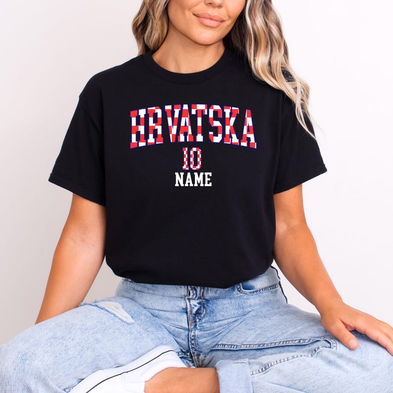 May include: A black short-sleeved t-shirt featuring the text HRVATSKA in a red and white checkered pattern, with the number 10 and the word NAME printed in white block lettering below the main text on the front of the garment.