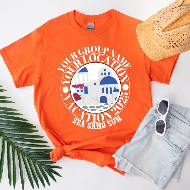 May include: Vibrant orange t-shirt with a circular graphic depicting white buildings with blue domes, and the text "Your Group Name Vacation 2023 Sea Sand Sun". A straw hat, sunglasses, and denim shorts are also visible.