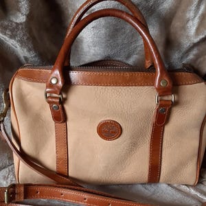 Bolso satchel Timberland clásico con asa superior, herrajes metálicos y correa de hombro desmontable. Piel y nobuk. Vídeo corto.