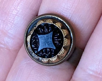 Ring - Antique Victorian era button repurposed into jewelry. Stamped brass border w/pressed black glass center - adjustable - 120+ years old