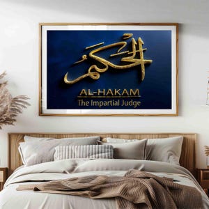 Puede incluir: Una impresión artística enmarcada con caligrafía árabe dorada sobre un fondo azul oscuro. El texto dice "AL-HAKAM The Impartial Judge" en letras doradas. La obra de arte se exhibe sobre una cama con ropa de cama de tonos neutros.