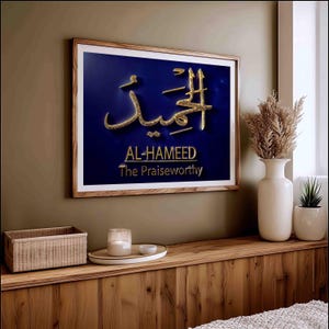 Puede incluir: Arte de pared enmarcado con caligrafía árabe dorada sobre fondo azul oscuro. El texto "AL-HAMEED The Praiseworthy" está debajo. El marco es de madera. Decoración para el hogar.