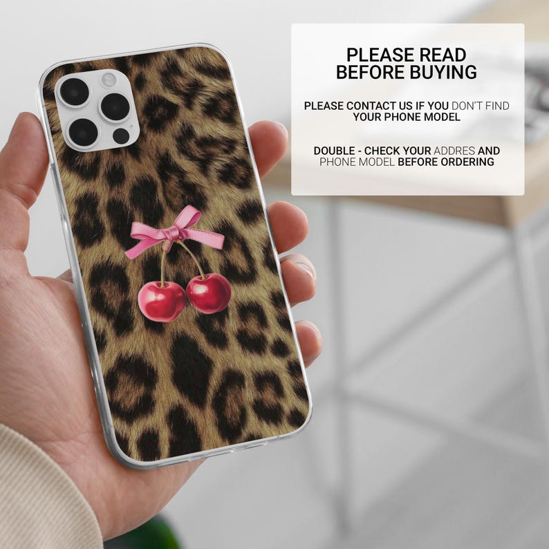 Puede incluir: Funda transparente para tel&eacute;fono con estampado de leopardo y un par de cerezas rojas atadas con un lazo rosa. La funda tiene un recorte para c&aacute;mara de tres lentes. El texto en la imagen dice "PLEASE READ BEFORE BUYING".