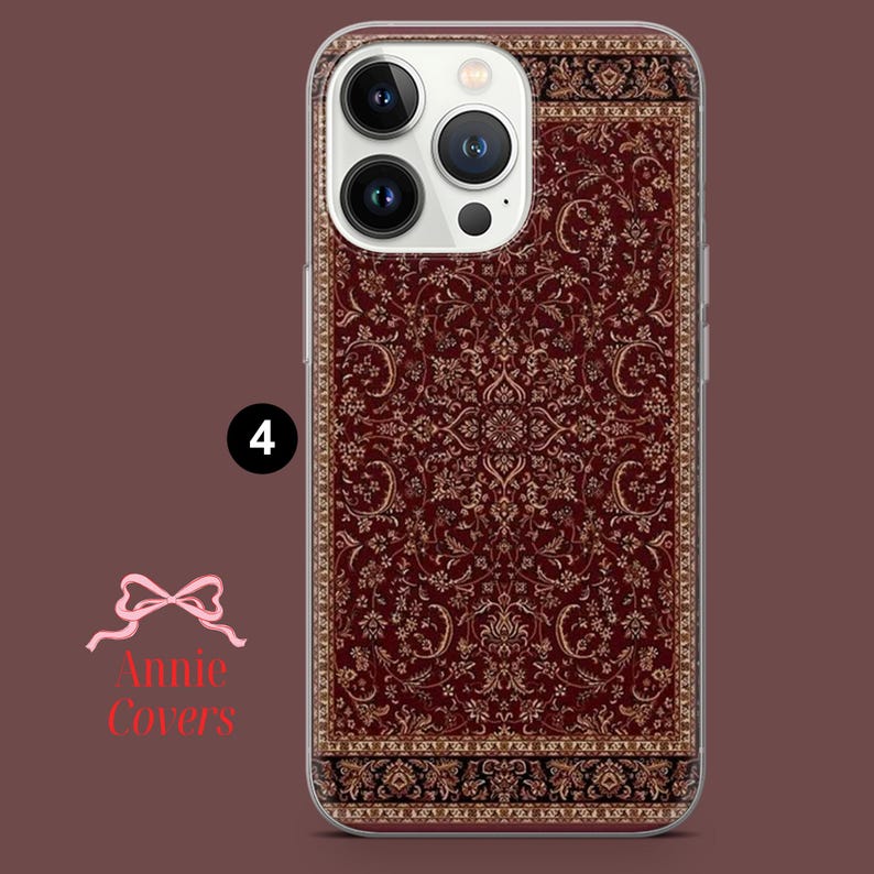May include: A clear phone case with a red and gold patterned design that resembles a rug. The case is designed for an iPhone with a camera bump.