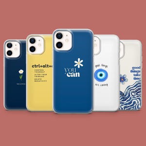 Pode incluir: Uma coleção de capas de telefone com vários designs e citações. As capas apresentam uma gama de cores, incluindo azul marinho, amarelo e branco. Algumas capas têm desenhos florais, enquanto outras exibem frases motivacionais como "You can" e "Good things take time."