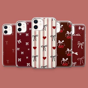 Może przedstawiać: Pięć różnych etui na telefon z różnymi wzorami. Etui są wszystkie przezroczyste i pokazują projekt telefonu. Jedno etui ma wzór w czerwono-białe paski z sercami i kokardkami. Inne etui ma wzór z czerwono-białych kokardek. Jeszcze inne etui ma wzór z czerwono-białych wiśni. Kolejne etui ma wzór z czerwono-białych kokardek. Ostatnie etui ma wzór z czerwono-białych kokardek.