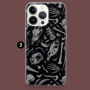 Pode incluir: Uma capa transparente para telefone com fundo preto e um padr&atilde;o branco de v&aacute;rios ossos e cr&acirc;nios.