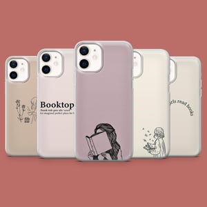 May include: Four clear phone cases with different designs. The first case has a floral design and the text "Booktop /book-toh-pee-uh/ noun An imagined perfect place for t". The second case has a drawing of a person reading a book. The third case has a simple design with a few white dots. The fourth case has a drawing of a person reading a book and the text "girls read books".