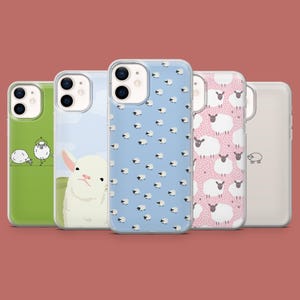 May include: Five clear phone cases with different sheep designs. The cases are all for an iPhone 13 Pro Max. The designs include a white sheep with a blue background, a pink background with white sheep, a green background with a white sheep, a blue background with white sheep, and a white sheep with a white background.