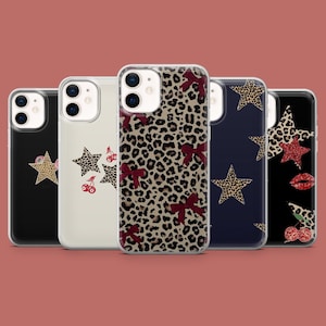 Op de afbeelding: Vijf verschillende telefoonhoesjes met verschillende ontwerpen. De hoesjes zijn allemaal transparant en laten het telefoonscherm zien. De ontwerpen omvatten een luipaardprint met rode strikken, een donkerblauw hoesje met een witte ster, een wit hoesje met een rode ster, een zwart hoesje met een rode ster en een zwart hoesje met een rode ster en kersen.