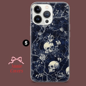 Puede incluir: Una funda transparente para tel&eacute;fono con un patr&oacute;n floral azul oscuro y blanco con calaveras. La funda tiene una protuberancia de c&aacute;mara elevada con un borde blanco.