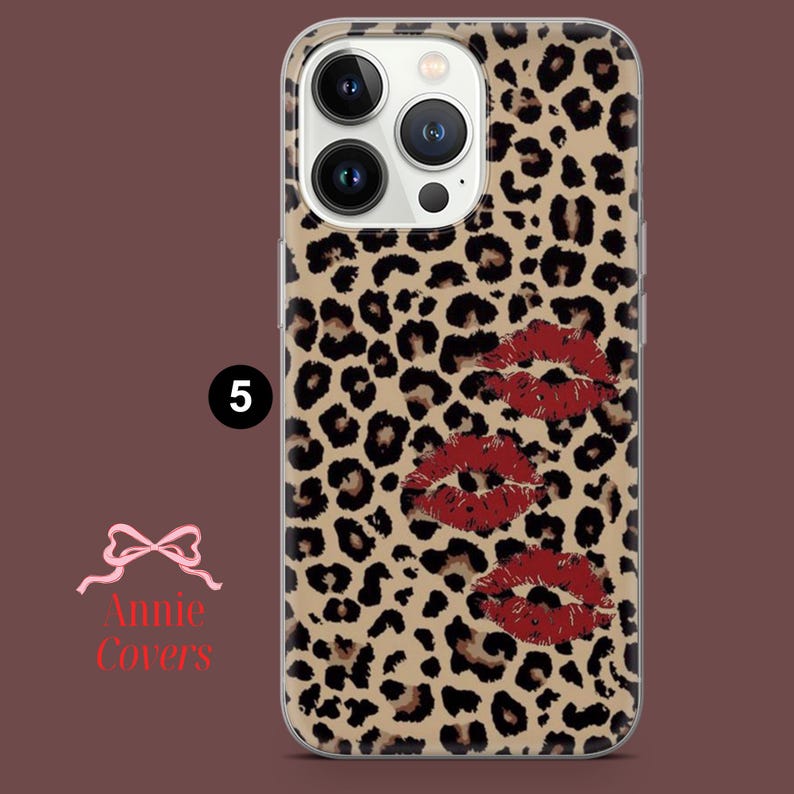 Puede incluir: Funda de tel&eacute;fono con estampado de leopardo y tres marcas de besos de l&aacute;piz labial rojo. La funda tiene un borde transparente y el n&uacute;mero "5" en un c&iacute;rculo negro. El logotipo de Annie Covers es visible.