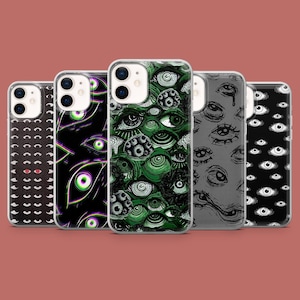 May include: Five different phone cases with eye designs. The cases are clear and show the phone's camera lens. The designs include black and white eyes, green and white eyes, and black and white eyes with a tear.