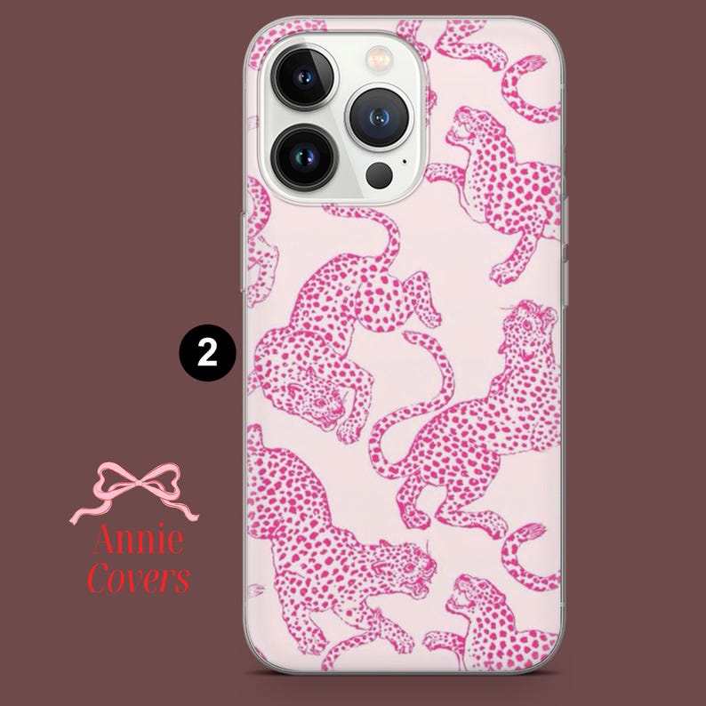Puede incluir: Funda transparente para tel&eacute;fono con un dise&ntilde;o de estampado de leopardo rosa. La funda tiene un patr&oacute;n repetido de leopardos rosas con manchas rosa oscuro sobre un fondo rosa claro. La funda tiene un recorte para la c&aacute;mara y el texto "2" es visible.