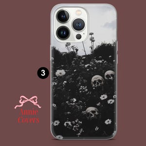 Puede incluir: Una funda de tel&eacute;fono transparente con una imagen en blanco y negro de cr&aacute;neos y flores. La funda de tel&eacute;fono est&aacute; dise&ntilde;ada para un iPhone con una protuberancia de c&aacute;mara.