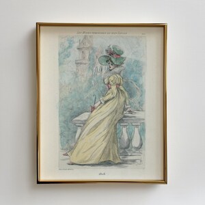Può includere: Un'illustrazione vintage incorniciata di una donna in un abito giallo e un cappello verde, seduta su un parapetto di pietra. L'illustrazione è intitolata "Les Modes Feminines du XIX Siecle" e datata "1866".