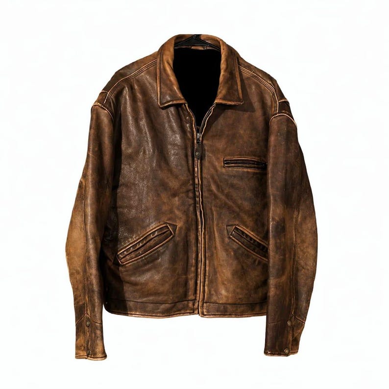 May include: A brown leather jacket with a zip-up front, two front pockets, and a small chest pocket. The jacket has a collared neckline and buttoned cuffs. The leather has a distressed appearance, with variations in color and texture.