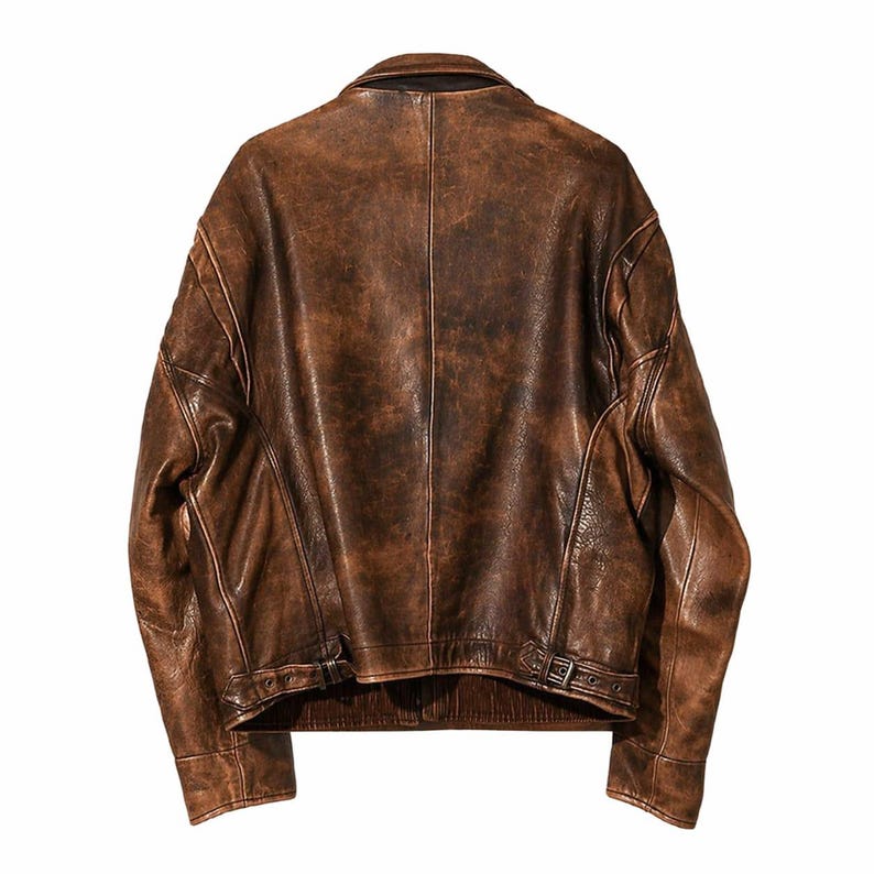 May include: A brown leather jacket with a distressed finish. The jacket features a classic collar, shoulder detailing, and a belt at the waist. The back view showcases the jacket's stitching and texture, with a vintage aesthetic.