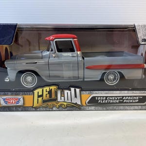 May include: A gray 1958 Chevy Apache Fleetside pickup truck model with a red roof and trim, displayed in a clear plastic box. The model has detailed wheels and is labeled as an adult collectible.
