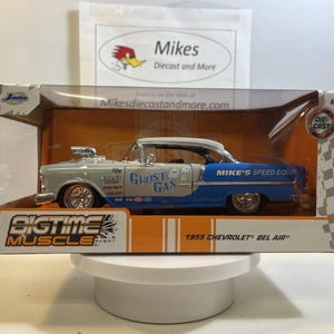 May include: A Jada Bigtime Muscle 1955 Chevrolet Bel Air die-cast model car in a display box. The car is two-toned with a light gray front and blue rear, featuring Ghost Gas graphics, chrome wheels, and Mike's Speed Equipment branding on the side.