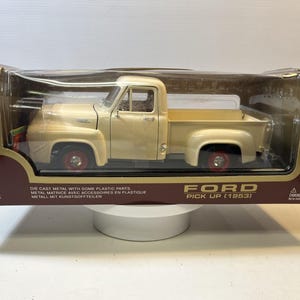 May include: A cream-colored 1953 Ford pickup truck die-cast model in its original packaging. The box features the text Ford Pick Up (1953) and Road Legends branding. The truck has red wheels and is visible through a clear plastic window.