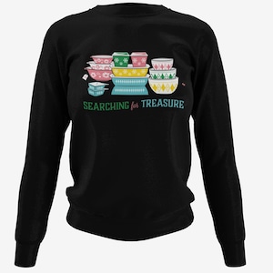 Puede incluir: Sudadera negra de manga larga con una pila de cuencos de mezcla vintage de colores y el texto "SEARCHING for TREASURE".