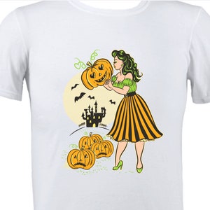 May include: A white t-shirt with a vintage-style illustration of a woman in a yellow and black striped skirt holding a jack-o'-lantern. The background features a spooky castle, bats, and a full moon.