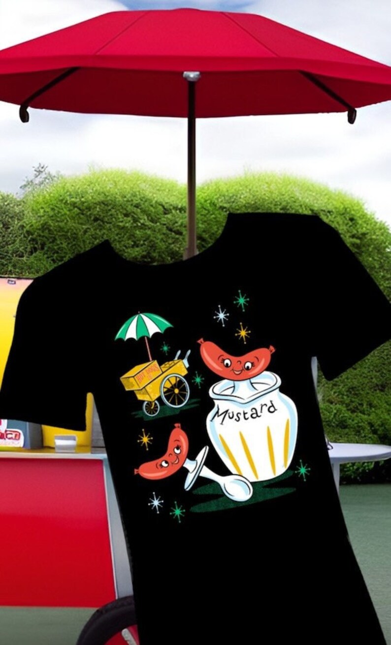 May include: Black t-shirt with a retro illustration of a hot dog cart, a smiling hot dog, and a jar of mustard. The hot dog is wearing a red and white hat and the mustard jar has a yellow lid and the word "Mustard" written on it.