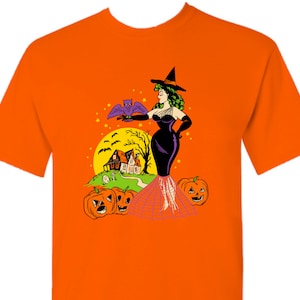 May include: Orange t-shirt with a vintage illustration of a witch in a black dress and hat, holding a bat. The witch is standing in front of a house with a moon and pumpkins in the background.