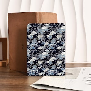 Può includere: Un oggetto decorativo rettangolare con un motivo a onde blu navy, bianco e azzurro. Il design presenta un motivo ripetuto di onde stilizzate, con accenti dorati. L'oggetto è posto su una superficie di legno.